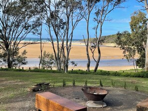 A beach view with trees, a wooden bench, and a wheelbarrow. - Reflections Moonee Beach - Holiday Park (Moonee Beach)