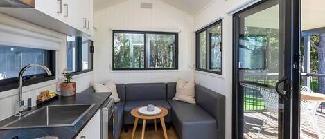 A compact kitchen with a built-in oven, a sink, and a dining area with a small table and a sofa.