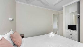 A hotel room with a bed, a television on a dresser, and a ceiling fan.