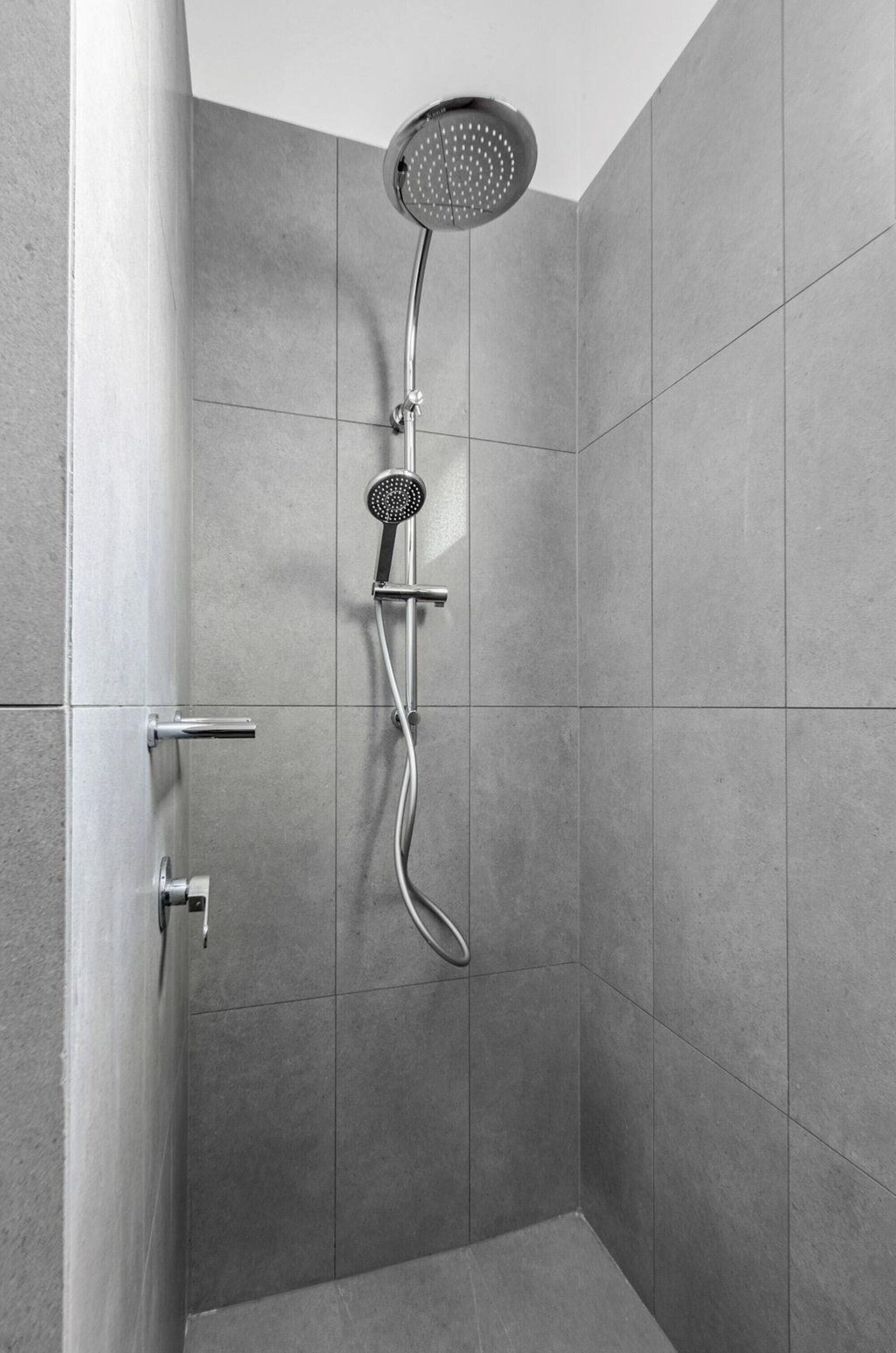Una ducha moderna con cabezal de ducha manual y grifería empotrada.