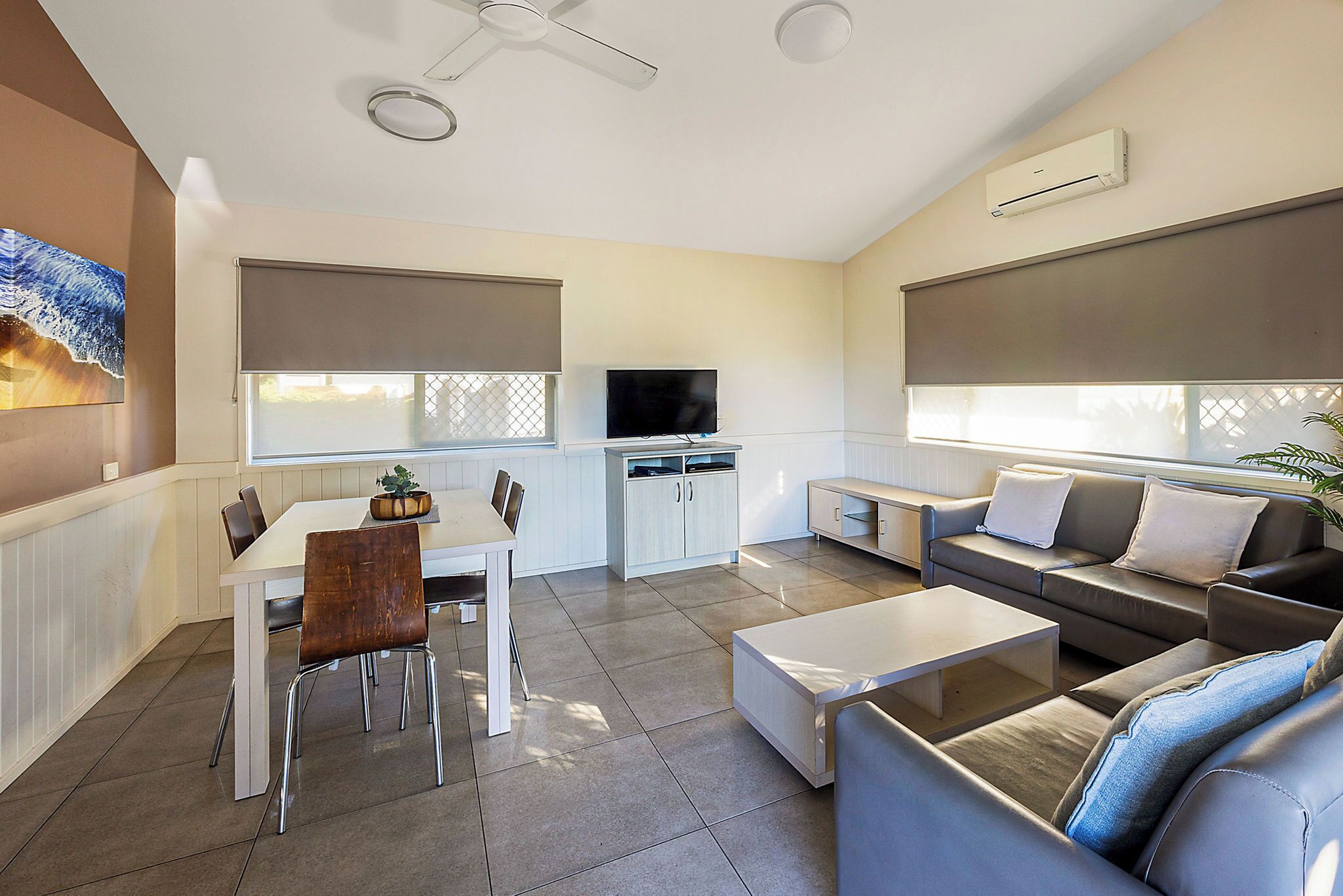 Una sala de estar moderna con comedor, televisor y ventilador de techo.