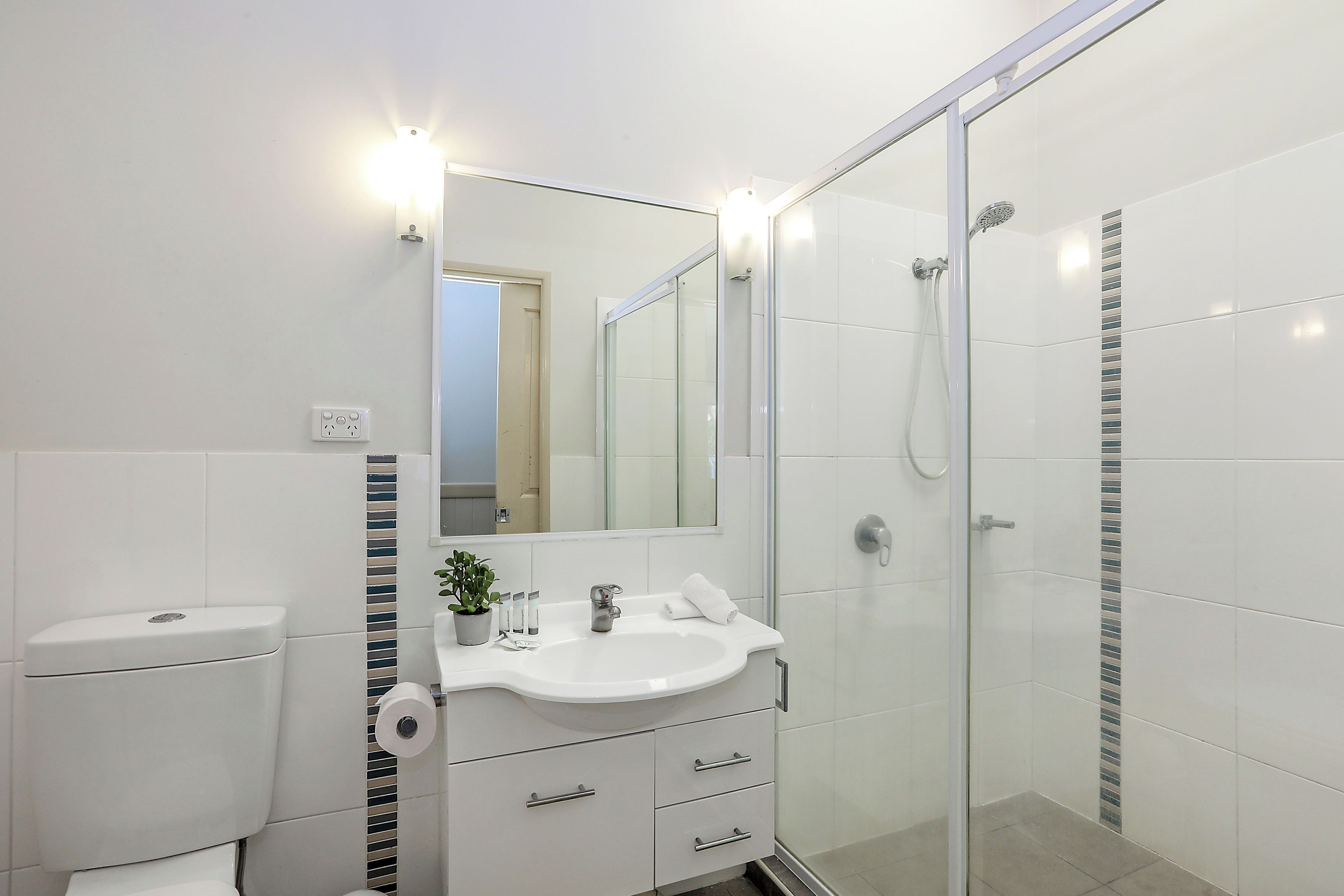 A modern bathroom with a glass shower enclosure, a white sink, and a mirror above it.