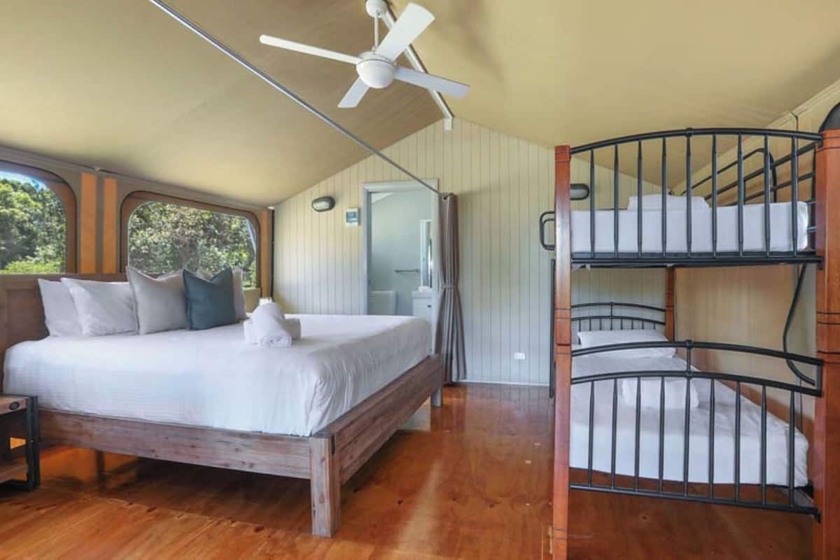 A bedroom with a wooden bed, a bunk bed, and a ceiling fan.