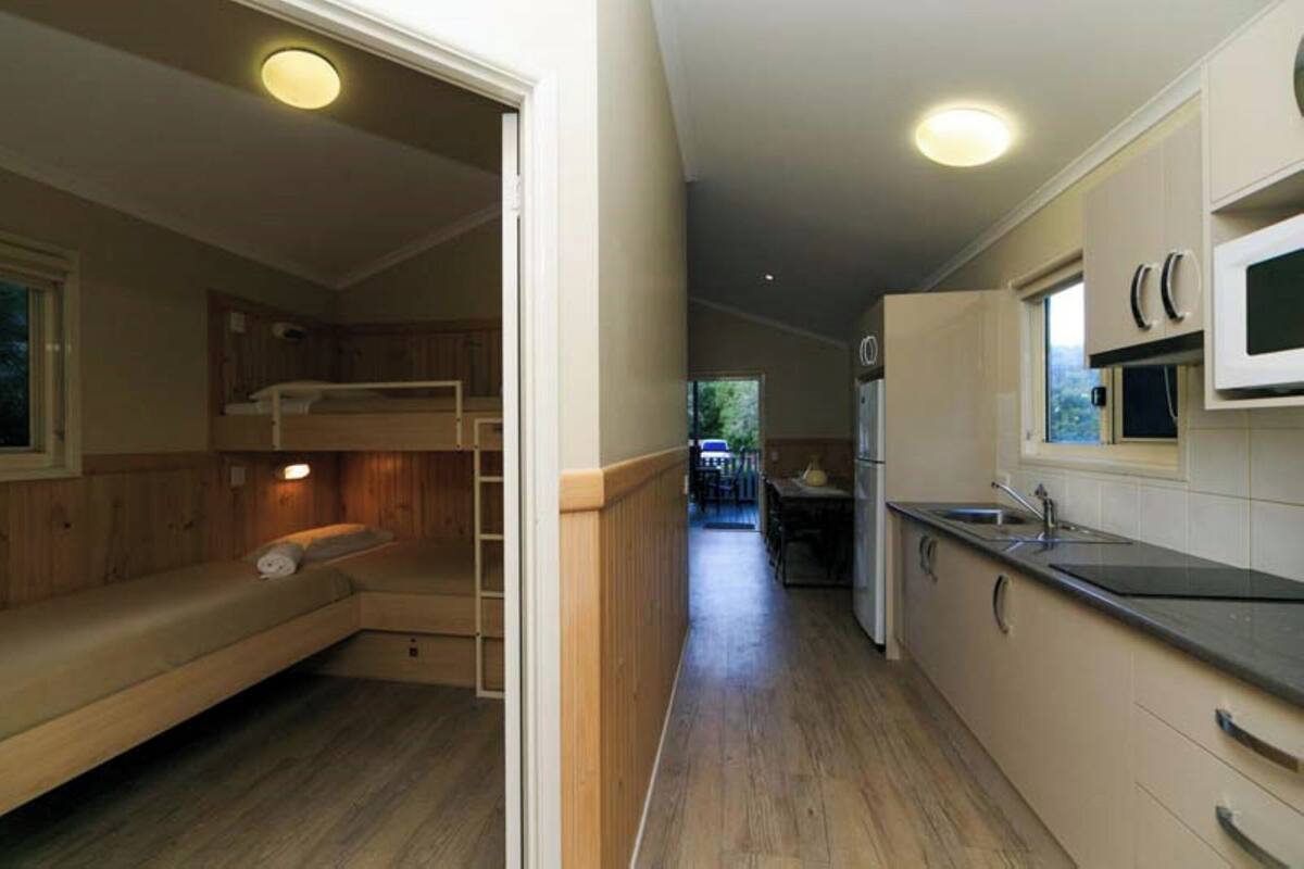 A compact RV interior with a bunk bed, kitchenette, and a small dining area.