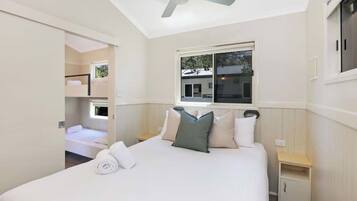 A bedroom with a bed, a ceiling fan, a window, and a nightstand.