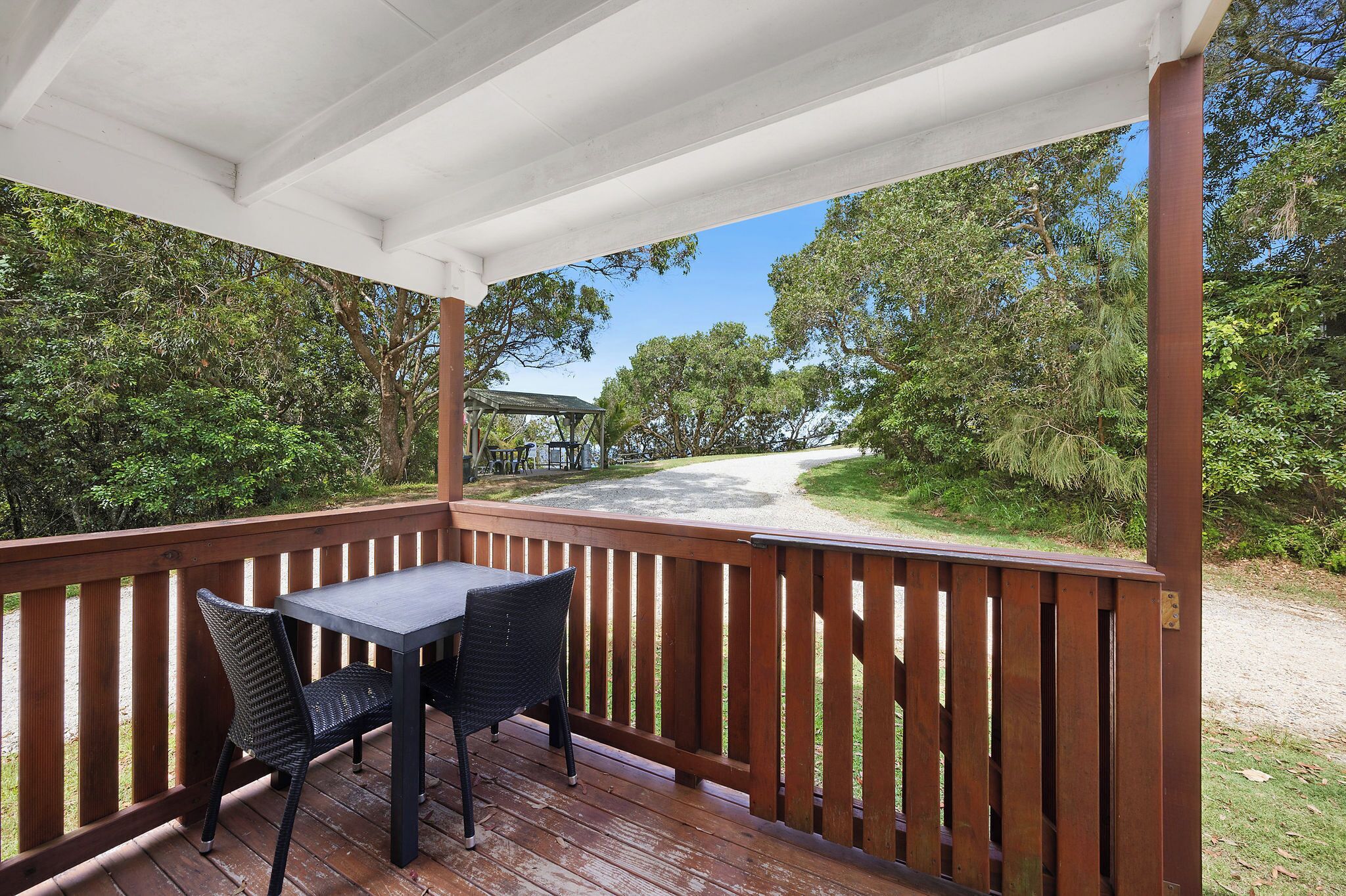 A covered outdoor area with a wooden deck, a table, and chairs.