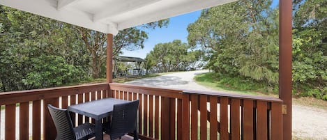 A covered outdoor area with a wooden deck, a table, and chairs.
