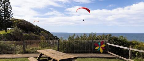 A picnic table in a grassy area with a view of the sea and a pinwheel decoration.