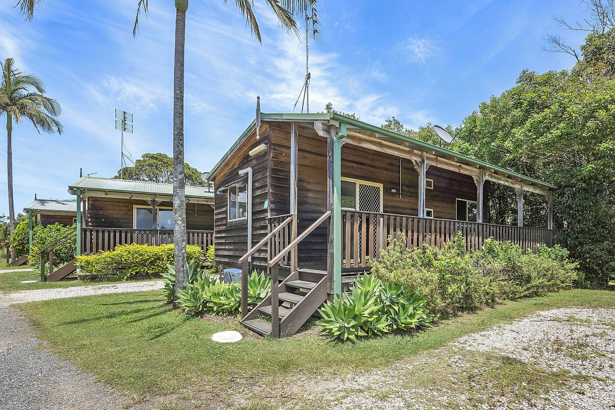 Een houten chalet met een veranda, trap en een schotelantenne.