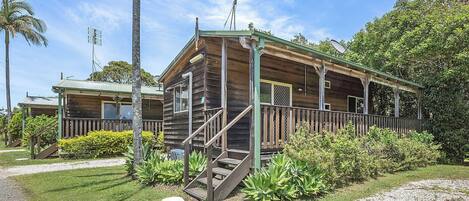 Een houten chalet met een veranda, trap en een schotelantenne.