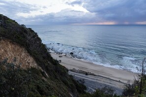A coastal landscape with a beach, rocky shoreline, and vegetation. - Reflections Nambucca Heads - Holiday Park (Nambucca Heads)