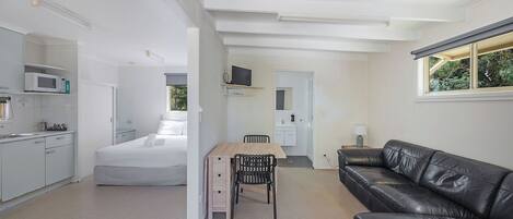 A modern, compact living space with a kitchenette, a dining area, and a living room.