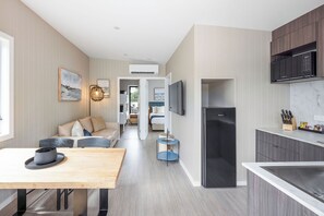 A modern kitchen with a black refrigerator, wooden dining table, and a built-in microwave. - Reflections Scotts Head - Holiday Park (Scotts Head)