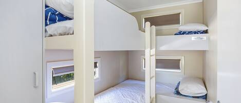 A compact room with bunk beds, a window, and a door.