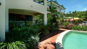 A hotel with a swimming pool, outdoor seating, and lush landscaping. - The Mediterranean Beachfront Apartments (Yorkeys Knob)