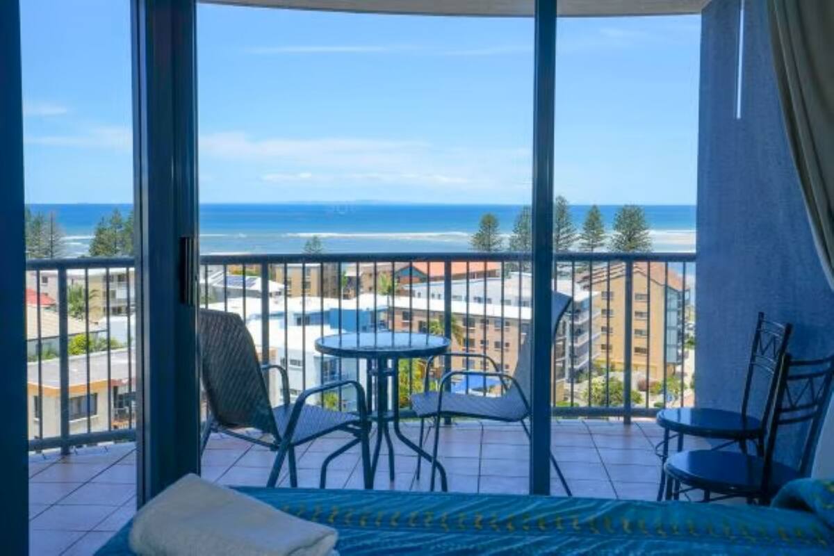 A balcony with a bed, chairs, and a small table.