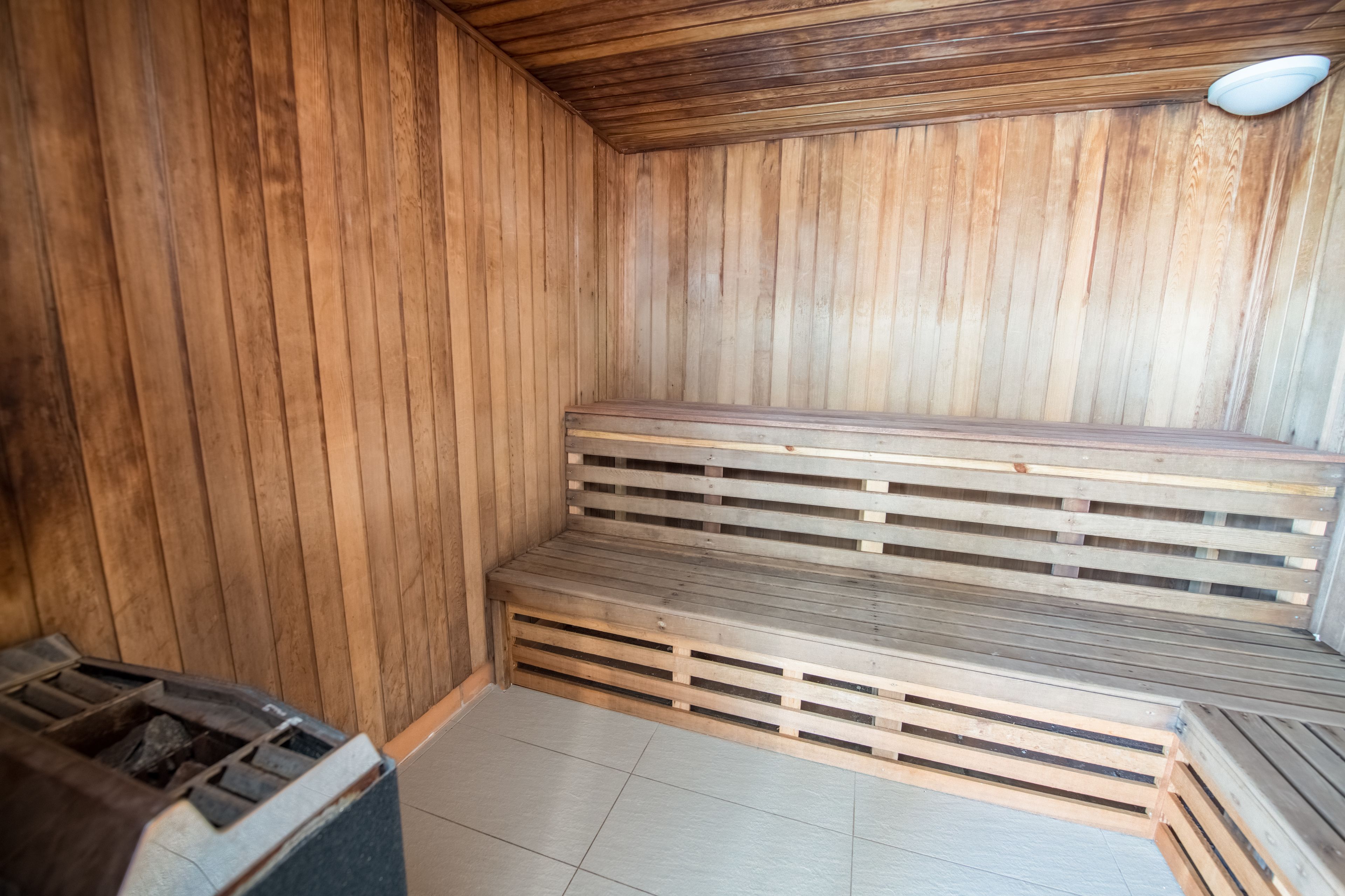 Sauna, jossa on puiset lauteet ja laatoitettu lattia.