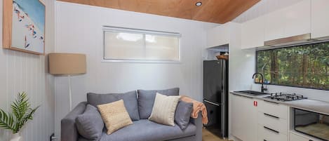 A modern kitchen with a grey sofa, a small dining table, and a skylight above.