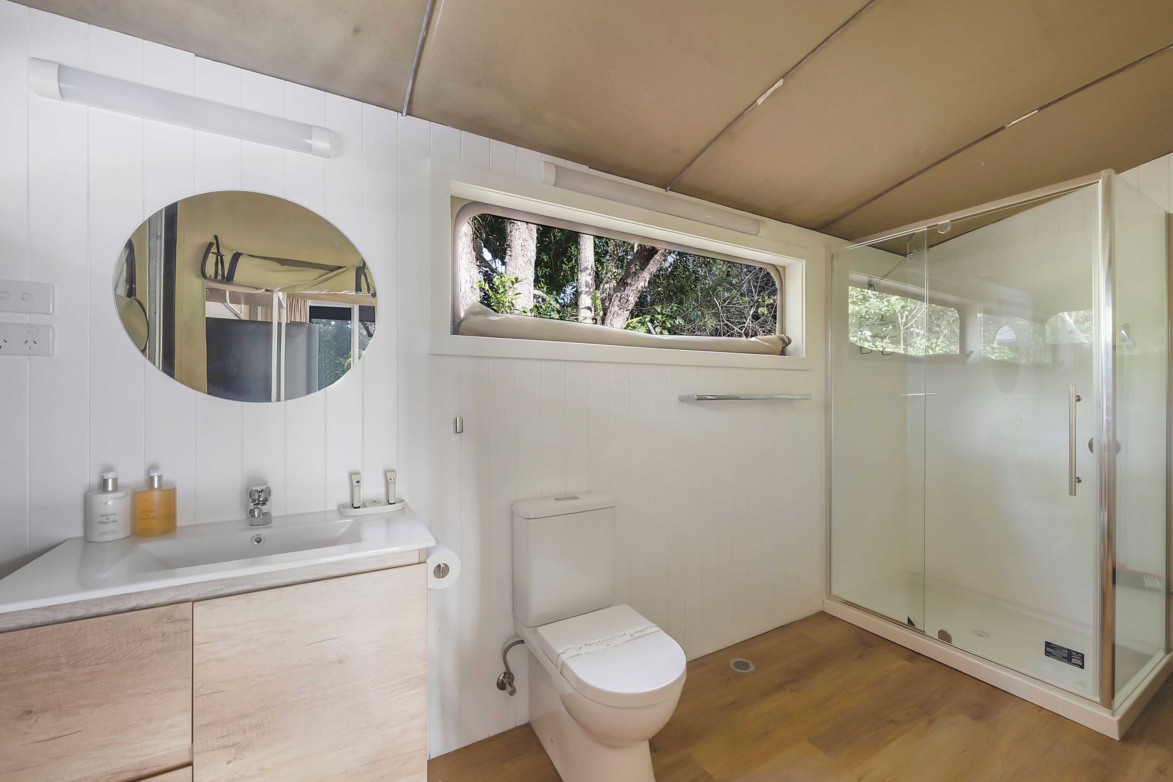 Een moderne badkamer met toilet, wastafel en douchecabine met glazen wanden.