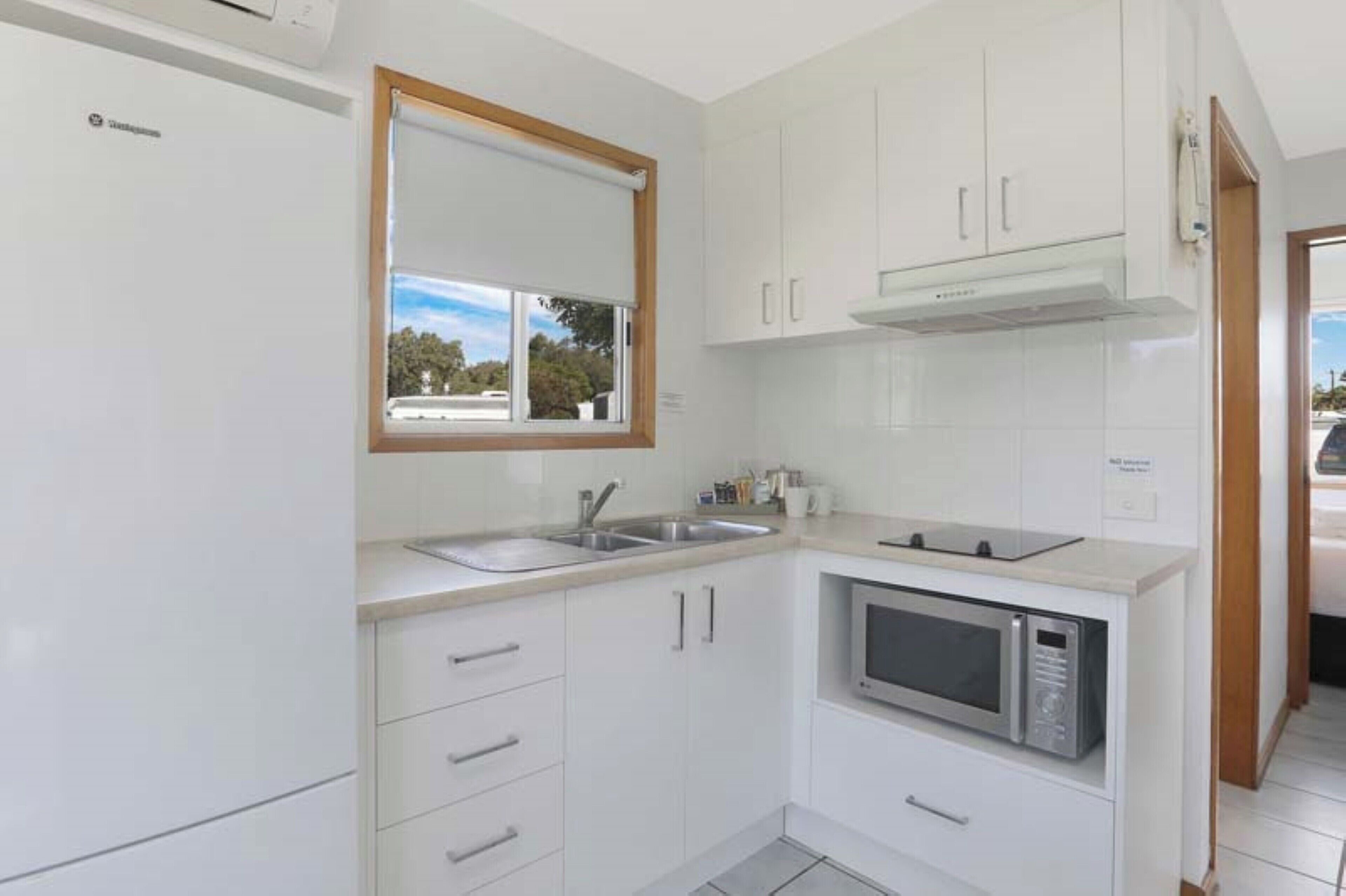 A modern kitchen with white cabinets, a built-in microwave, and a window with a view of greenery.