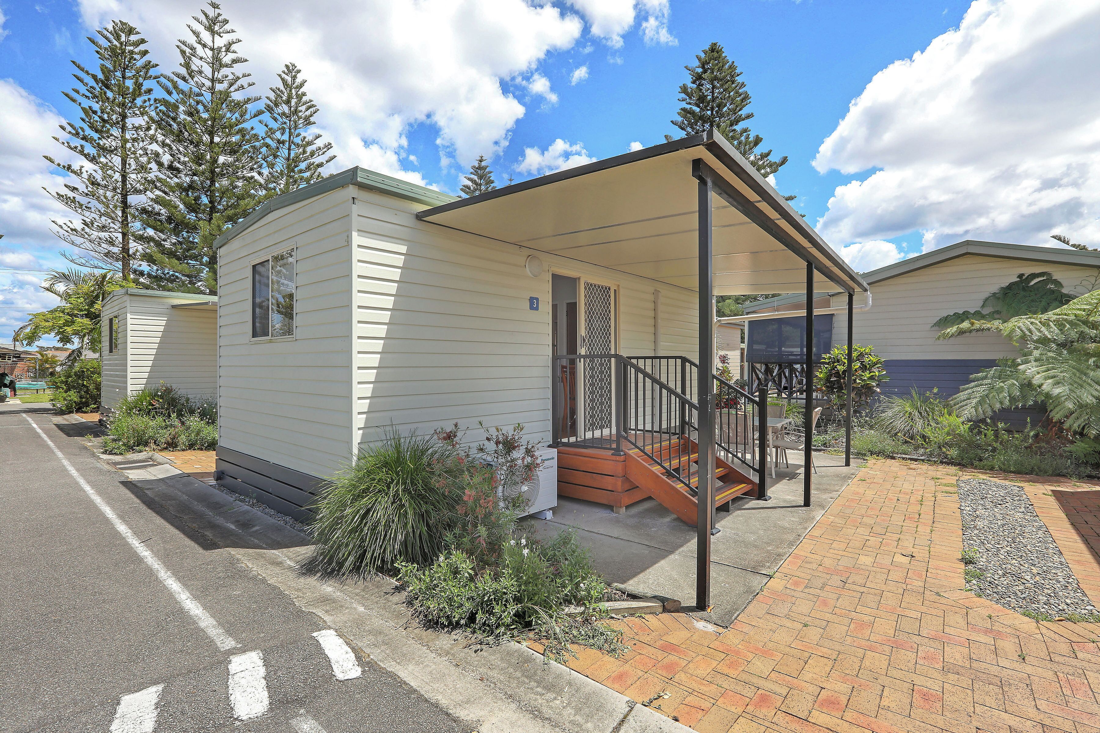A small, single-story mobile home with a covered porch and a small staircase leading to the entrance.