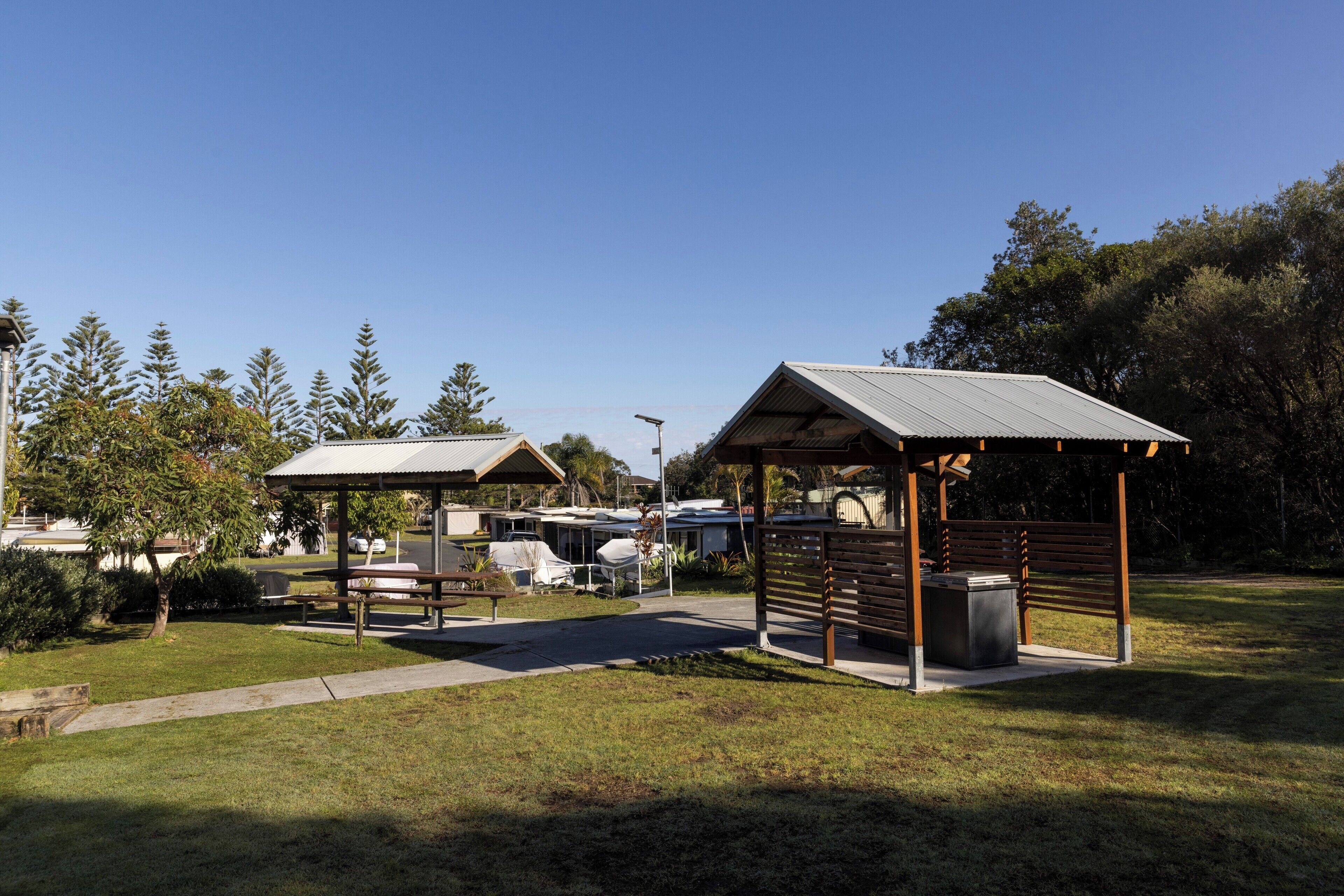 A park with two gazebos, picnic tables, and a paved walkway.
