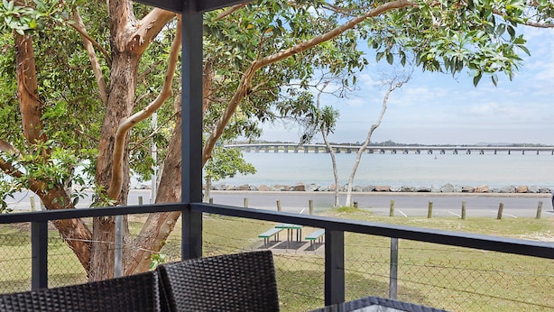A covered outdoor seating area with a view of a river and a bridge.