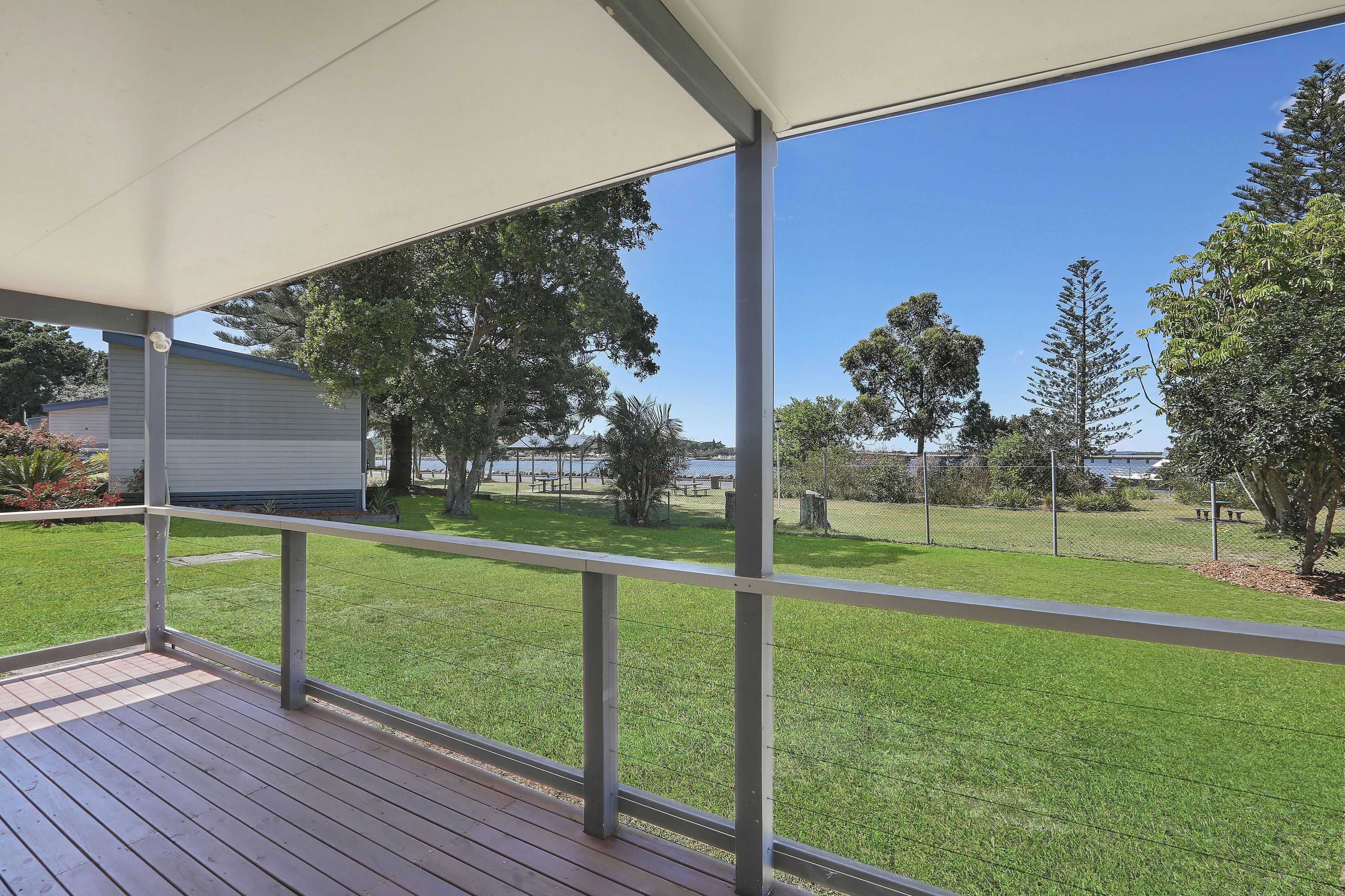 A covered outdoor area with a view of a grassy yard and trees.