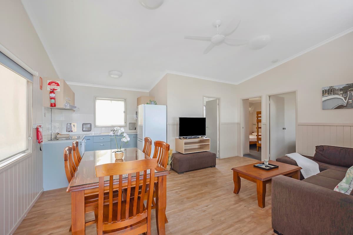 A spacious living area with a wooden dining table, a sofa, and a television.