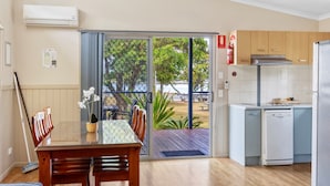 A modern kitchen with a dining area, a sliding glass door leading to a deck, and a small dishwasher.