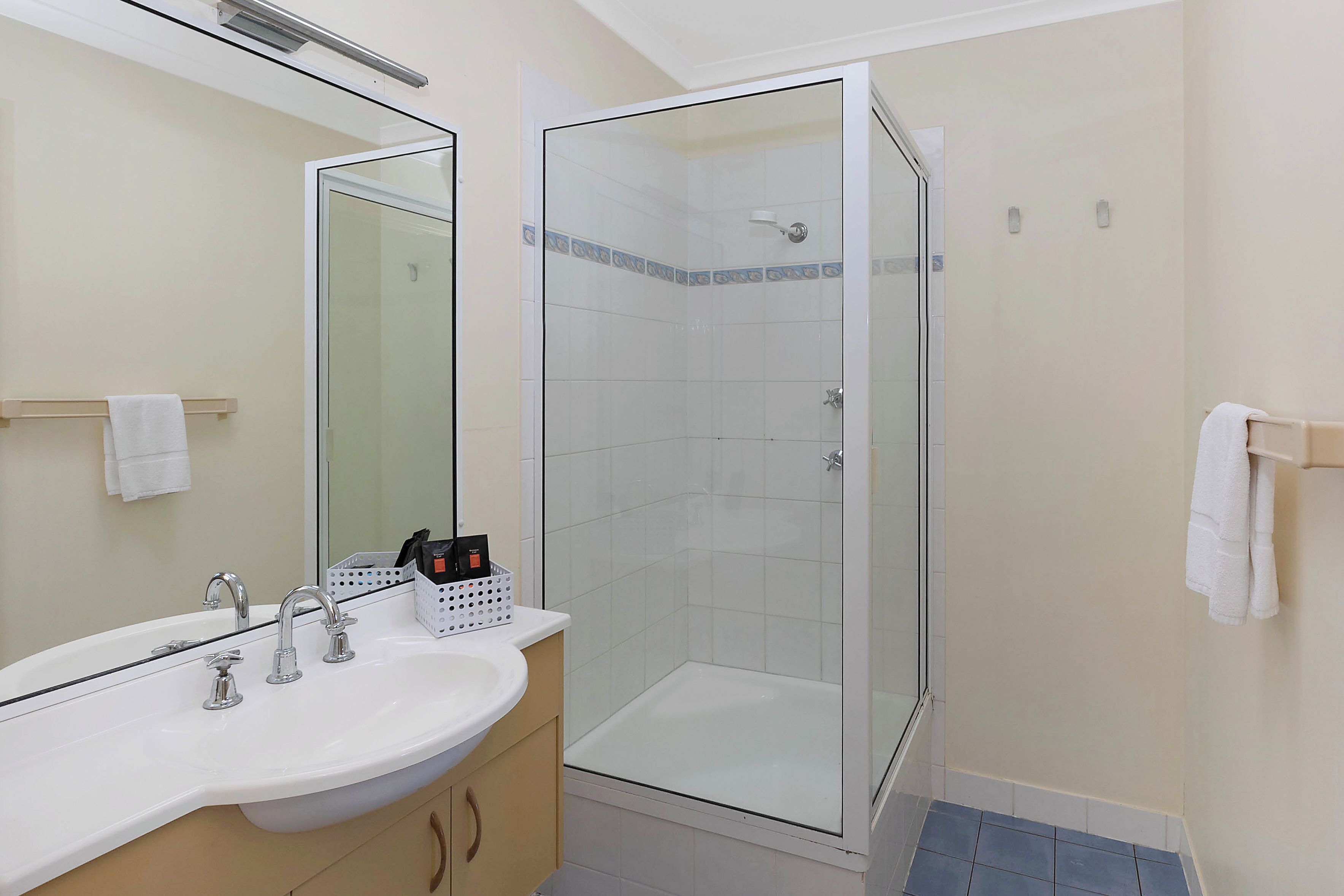 Ein Badezimmer mit einem weißen Waschbecken, einem Spiegel und einer Duschkabine.