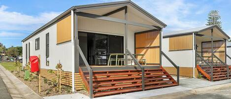 A modern, single-story house with a covered porch, a small staircase, and a satellite dish.