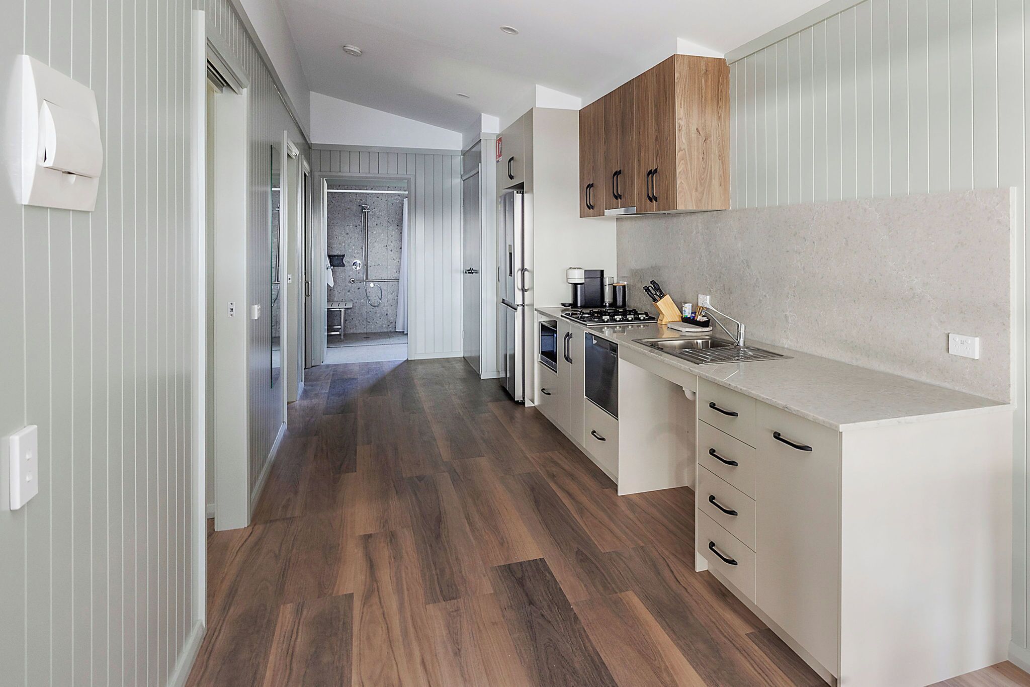 A modern kitchen with wooden cabinets, a built-in oven, and a stainless steel sink.
