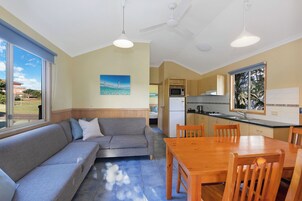 Una cocina moderna con comedor, un sofá gris y vistas al exterior.