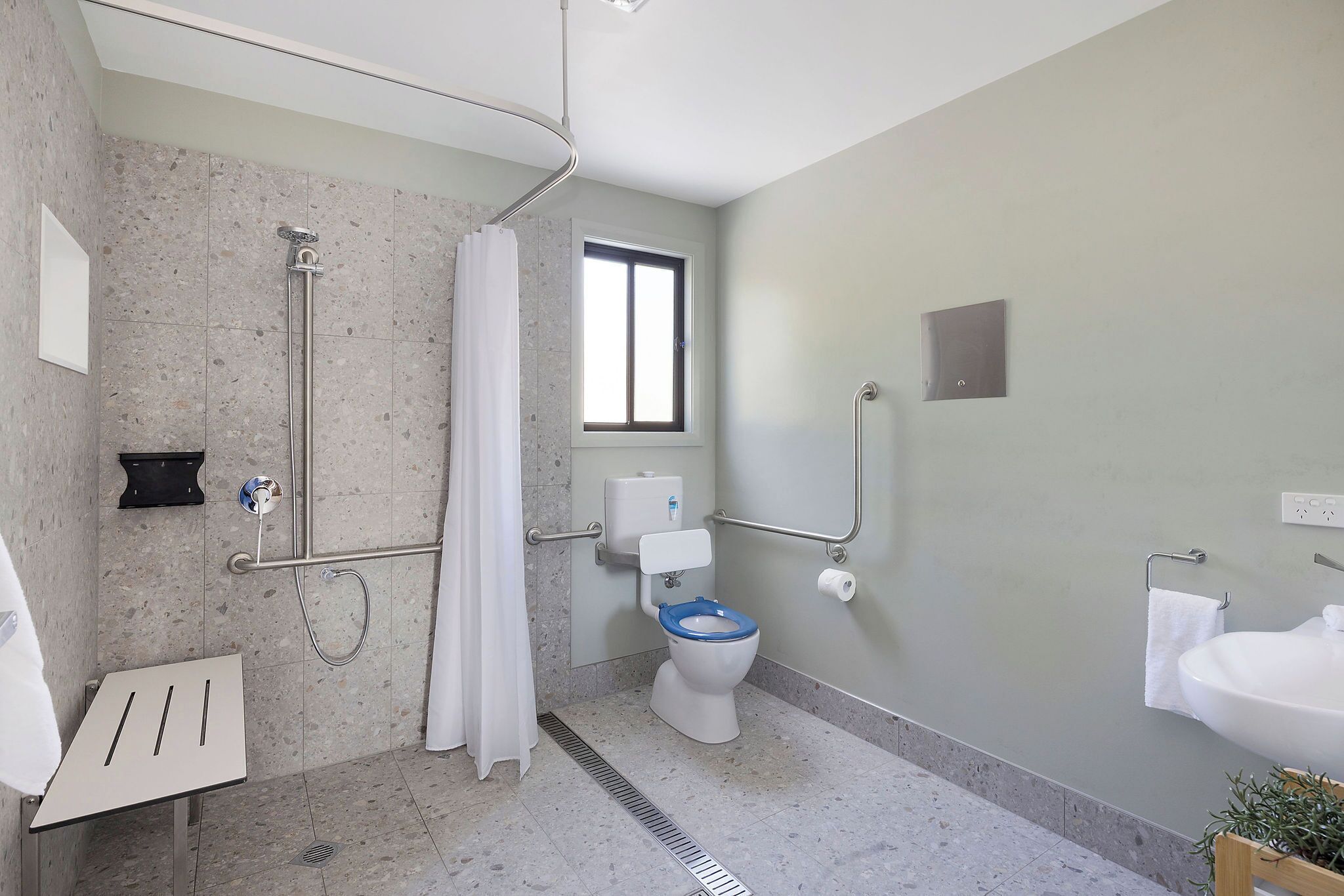 A modern bathroom with a shower, toilet, and sink.