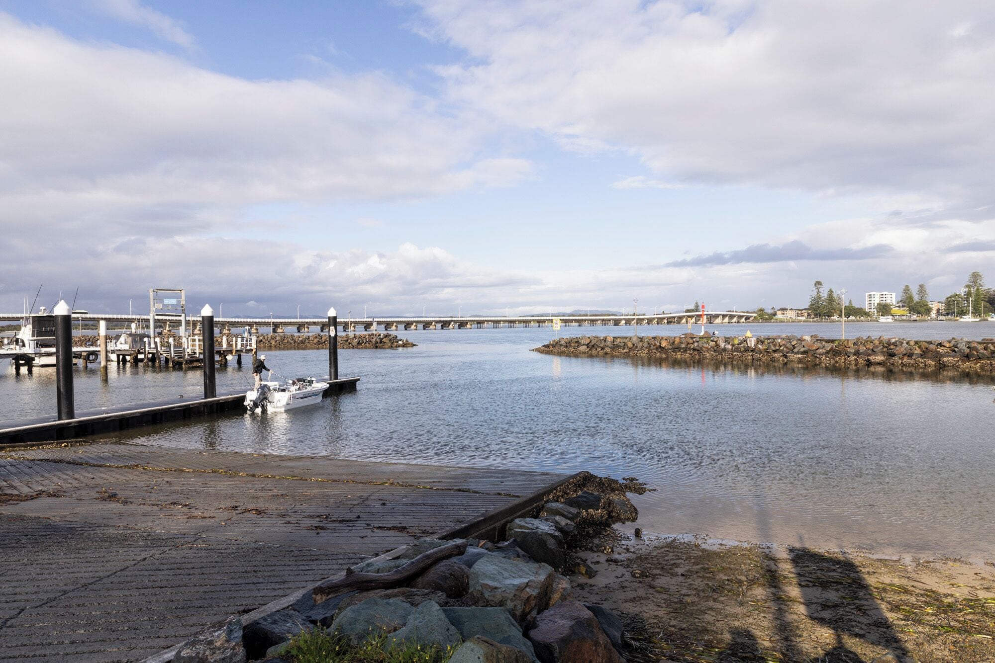 A waterfront dock with boats, a pier extending into the water, and a rocky shoreline.