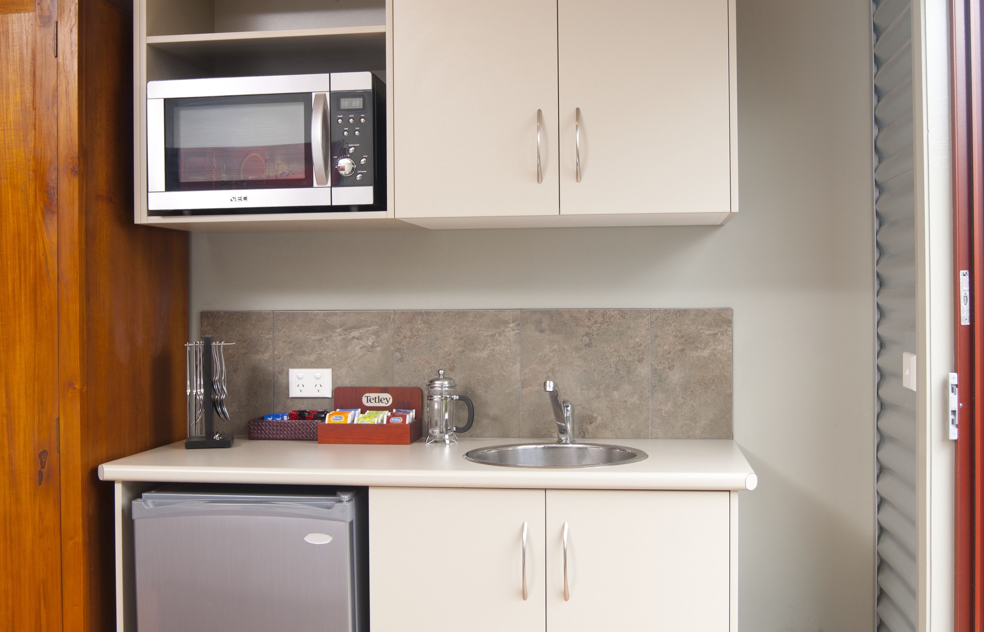 A compact kitchenette with a microwave, sink, and small refrigerator.