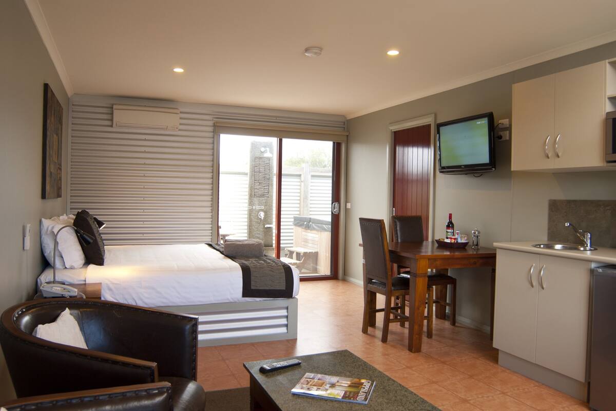Une chambre d’hôtel comprenant un lit, un bureau, une télévision, un coin repas et une kitchenette.
