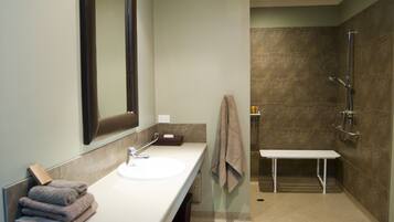 A modern bathroom with a white sink, a large mirror, a towel rack, and a shower area.