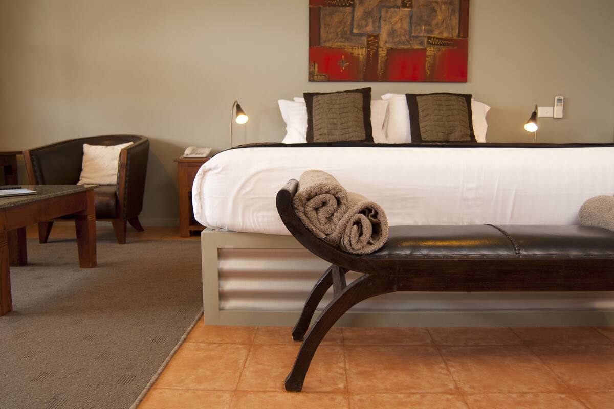 Une chambre d’hôtel avec un lit, une banquette sur laquelle est posée une serviette pliée, un bureau et une chaise.