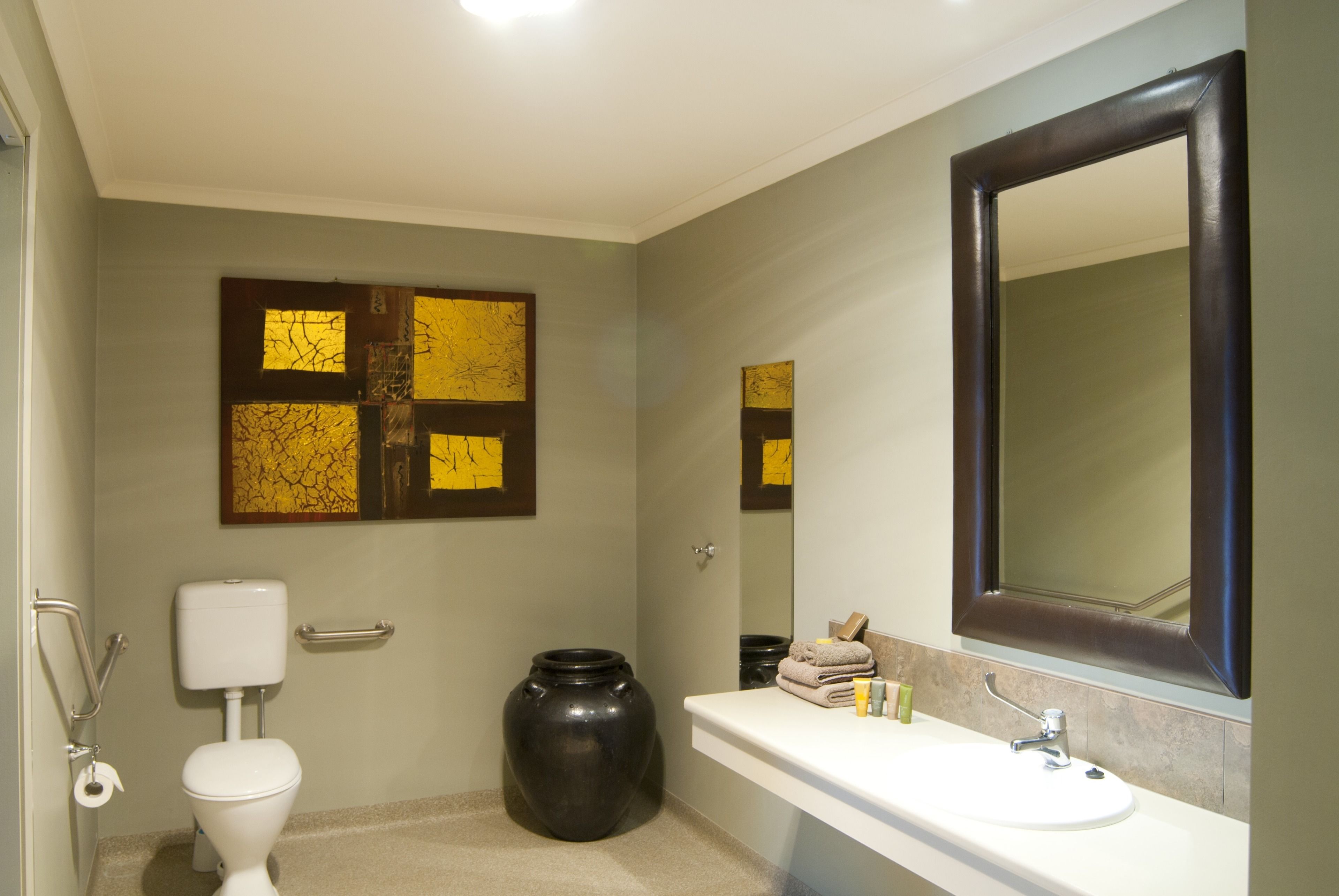 Un baño con inodoro, lavamanos, espejo y decoración en la pared.