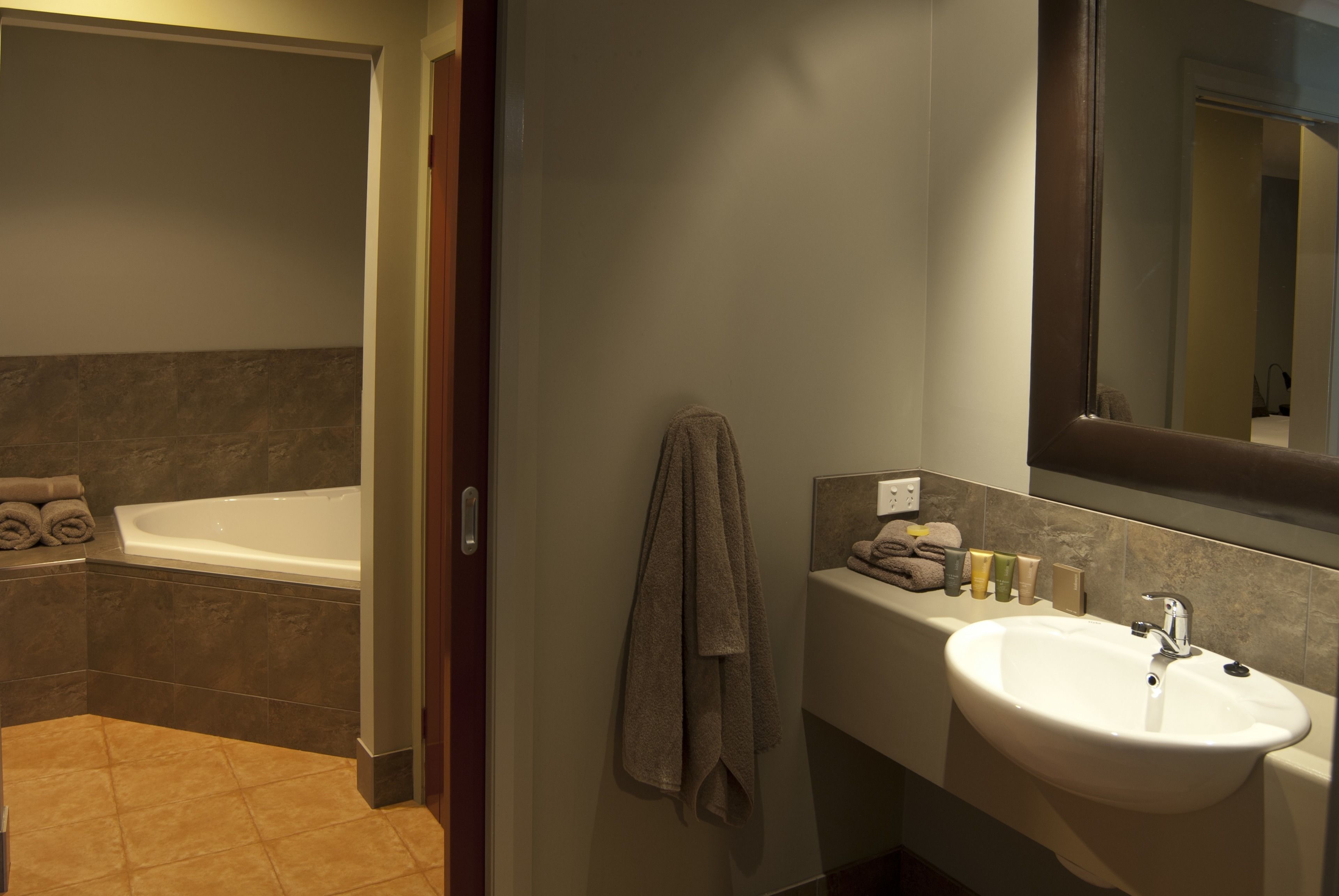 Un baño con bañera, lavamanos y espejo.