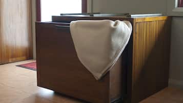 A wooden dresser with a beige towel draped over it, situated in a room with tiled flooring and a window in the background.