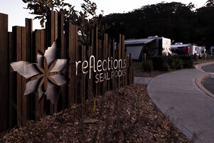 Uma placa de madeira com o texto 'reflections seal rocks' e um desenho de flor em metal.