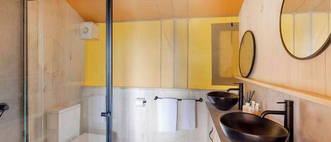 Un bagno moderno con box doccia in vetro, un water, un lavandino con lavabo nero e due specchi.