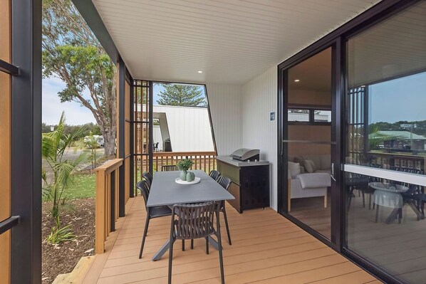 An outdoor patio with a table and chairs, a grill, and a view of the surrounding area.