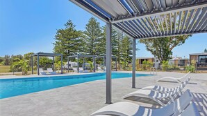 A swimming pool with lounge chairs and a pergola. - Reflections Hawks Nest - Holiday Park (Hawks Nest)