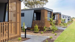 A row of modern, modular cabins with wooden railings and a well-maintained garden area. - Reflections Hawks Nest - Holiday Park (Hawks Nest)
