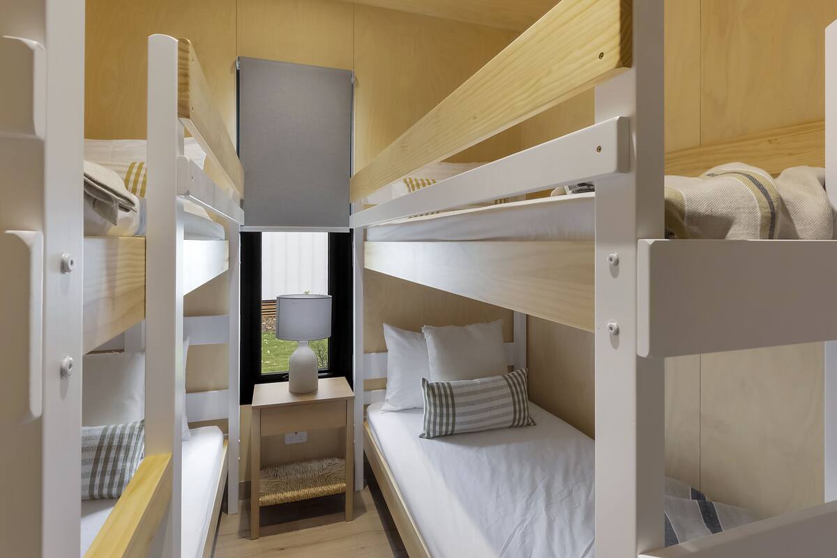A bunk bed room with a desk and a lamp.