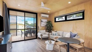 Una sala de estar moderna con sofá, mesa de centro, sillas, televisor y balcón con vistas.